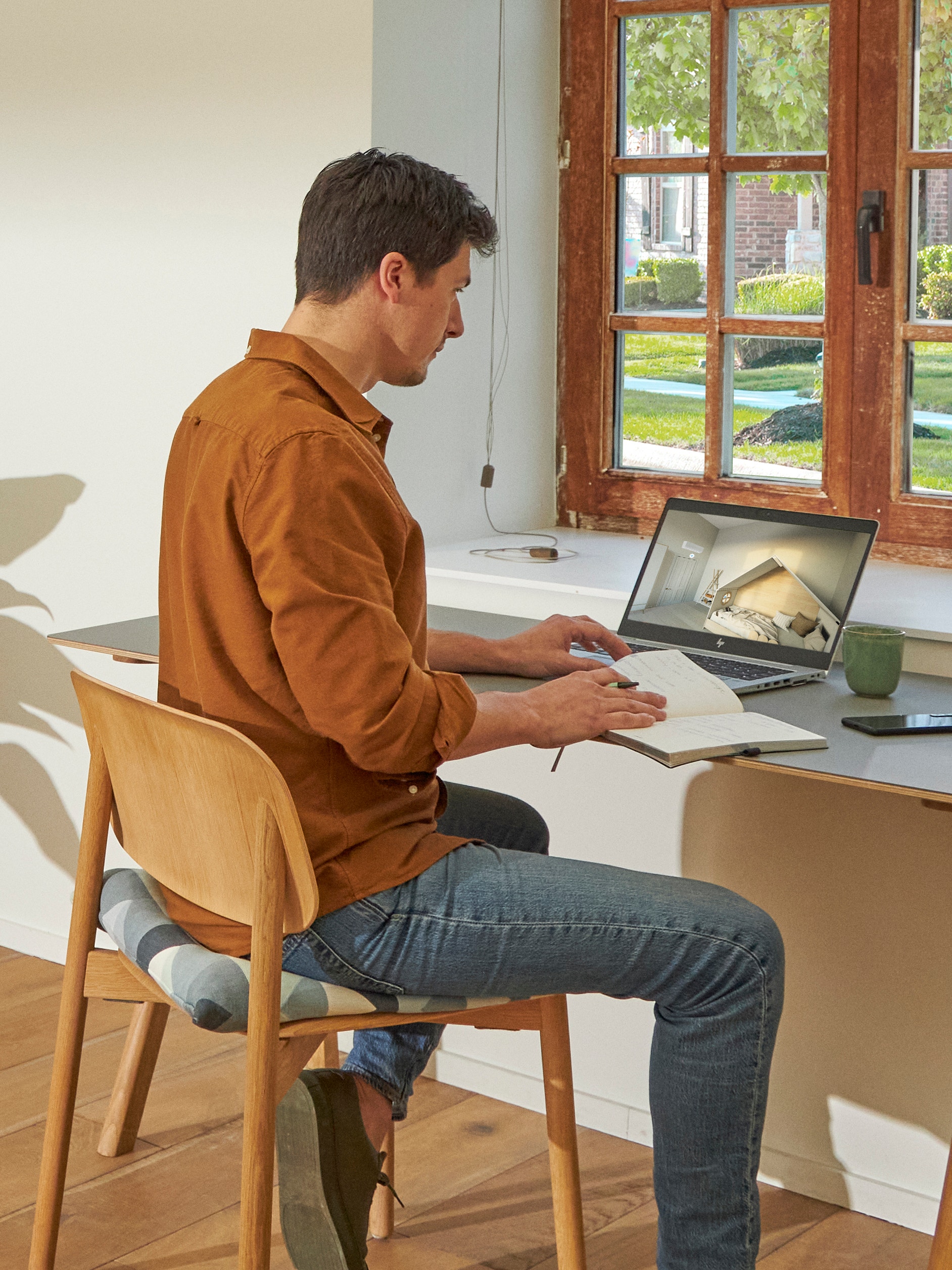 Man standing close to a window viewing air conditioners on the virtual experience centre on his laptop