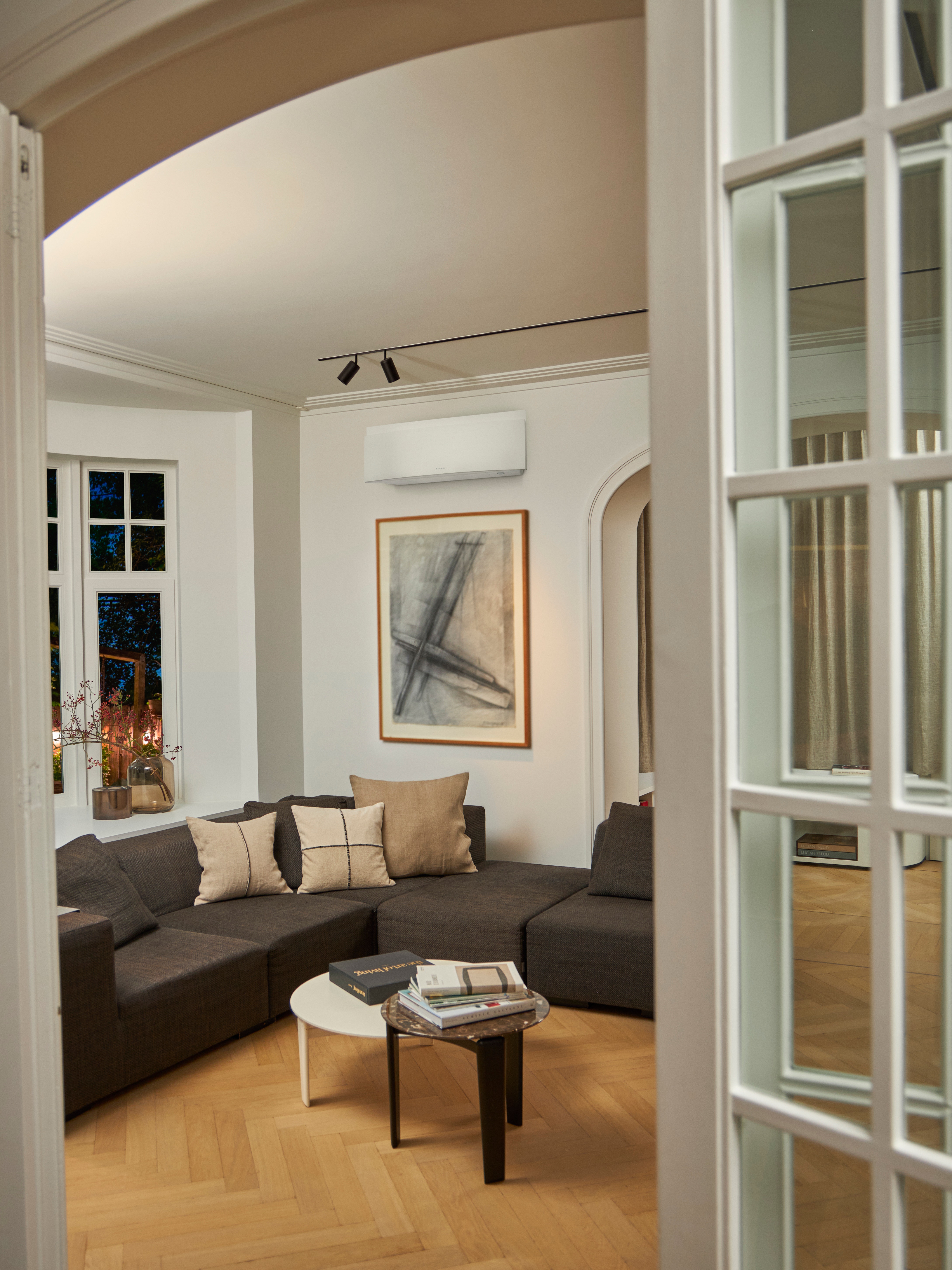 Living room with couch in it and a wall-mounted climate solution above it