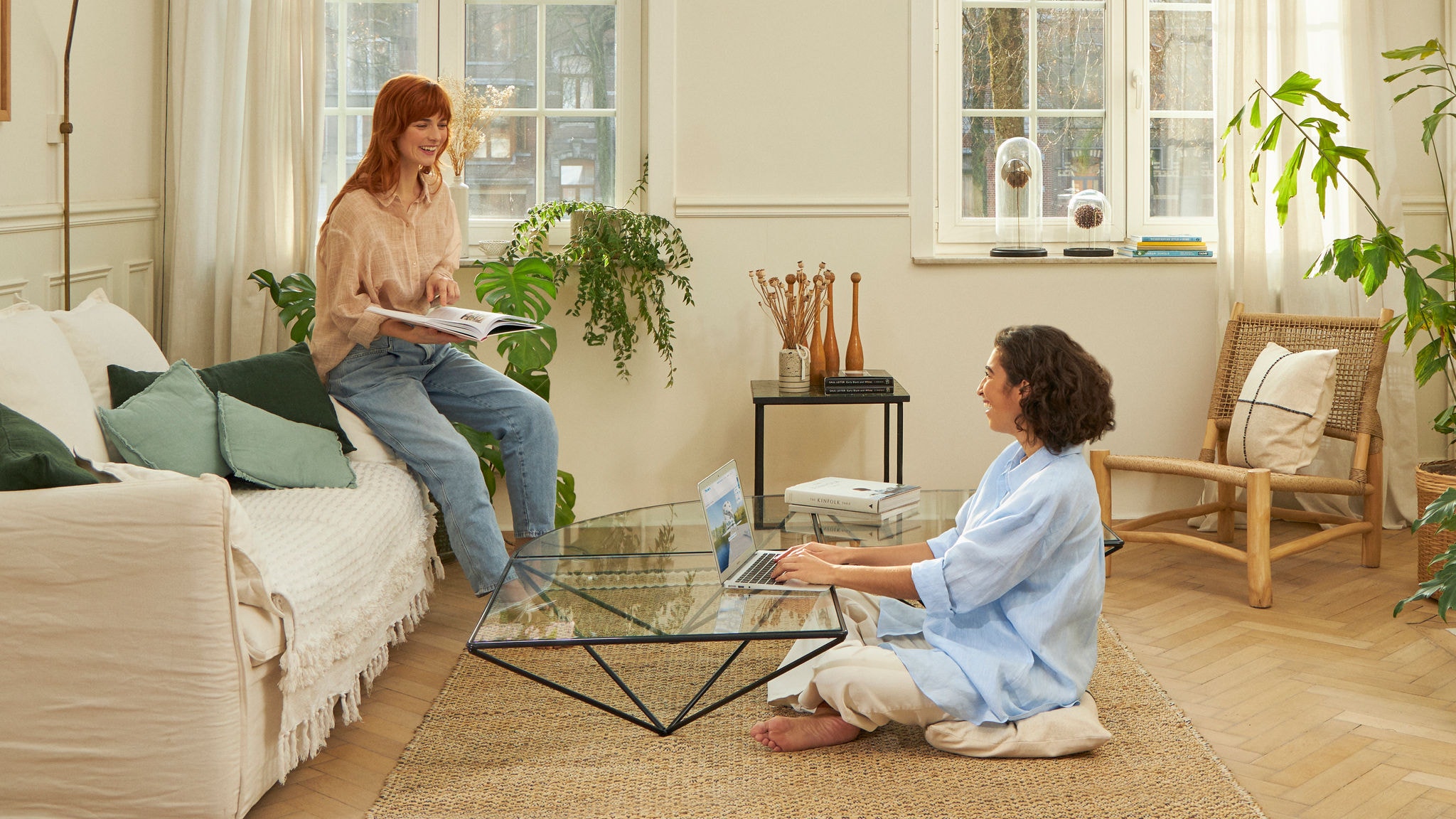 Two woman laughing in the living room while working and reading
